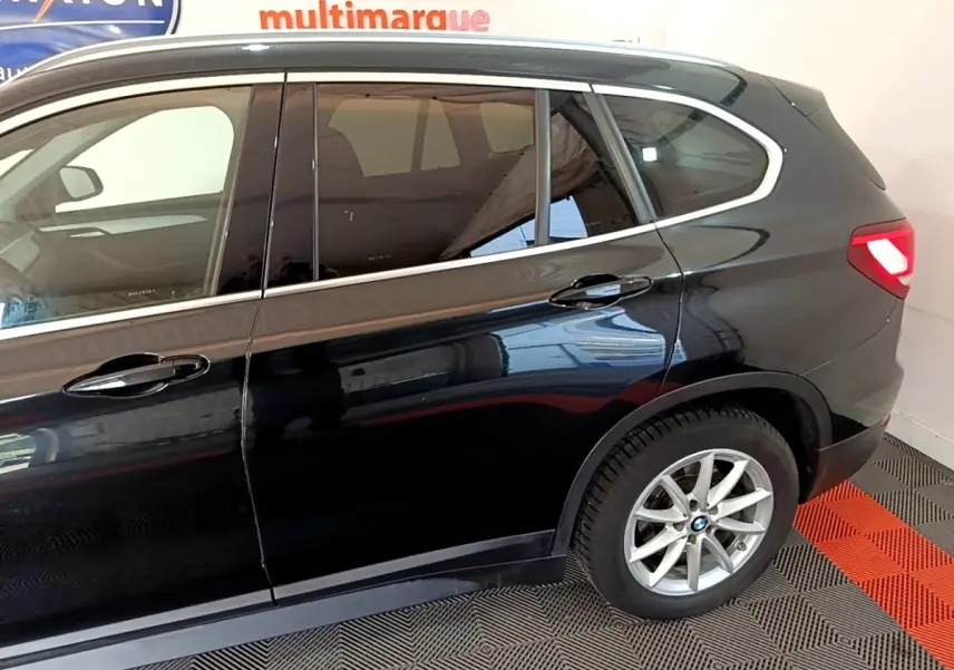 Vue latérale côté droit d'un BMW X1 noir 2020 avec jantes alliage et feux arrière allumés.