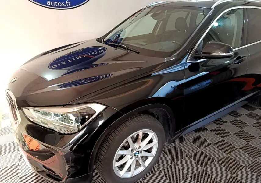 BMW X1 sDrive20i noir en 3/4 avant droit, mettant en valeur ses phares LED et jantes alliage argentées.