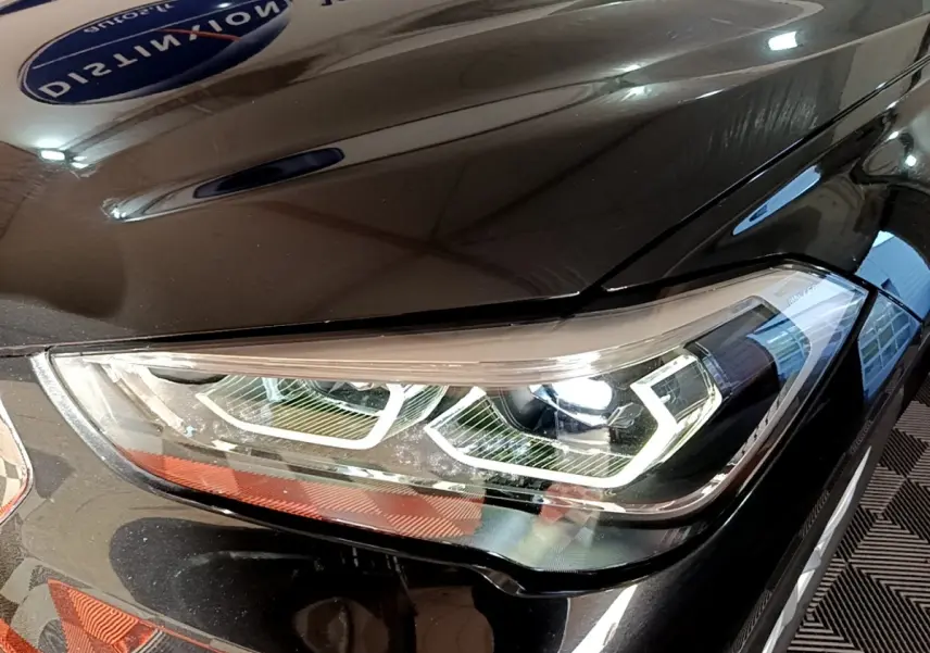 Gros plan sur le phare avant droit LED d’un BMW X1 noir, mettant en valeur les lignes modernes et précises du véhicule.
