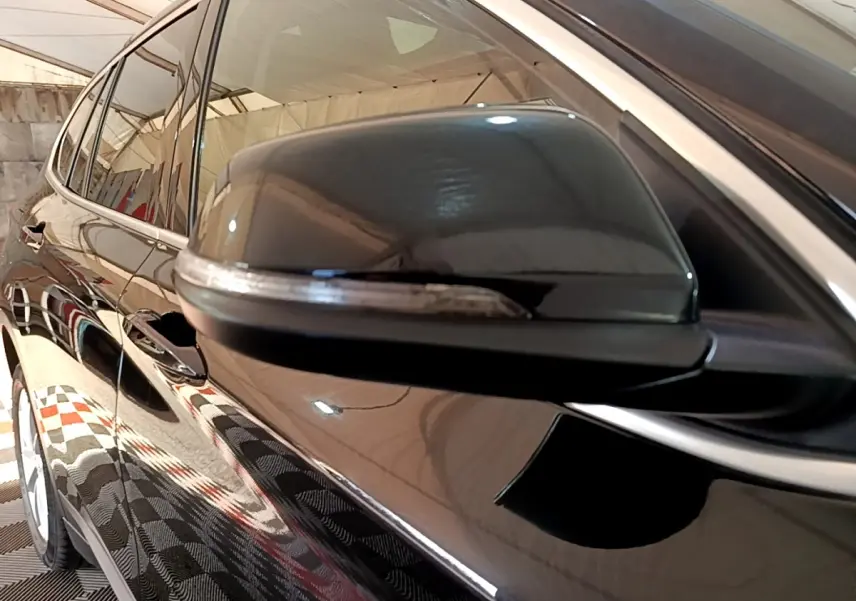 Gros plan sur le rétroviseur côté gauche noir brillant d’un BMW X1 sDrive20i Business Design 2020.