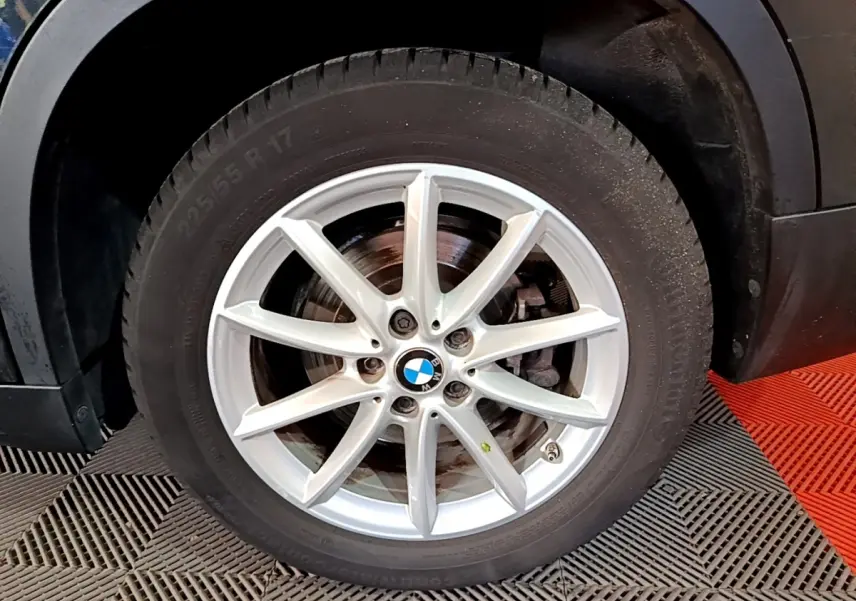 Gros plan sur la roue avant droite d’un BMW X1 noir, jante alliage argentée à 10 branches.