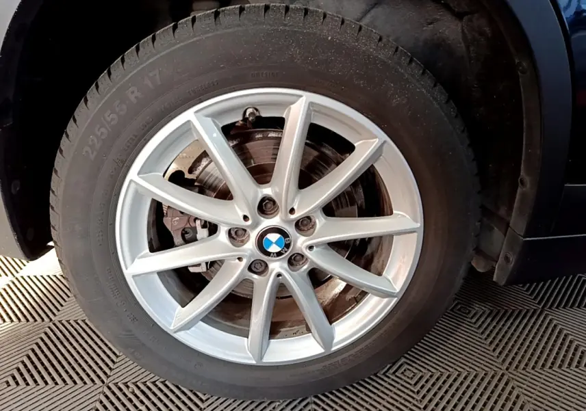 Gros plan sur la roue avant gauche avec jante alliage argentée du BMW X1 noir sDrive20i Business Design 2020.