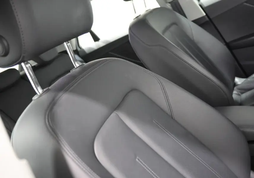 Gros plan sur les sièges avant en cuir noir de l'Audi Q2 TFSI 110, vue intérieure côté conducteur.