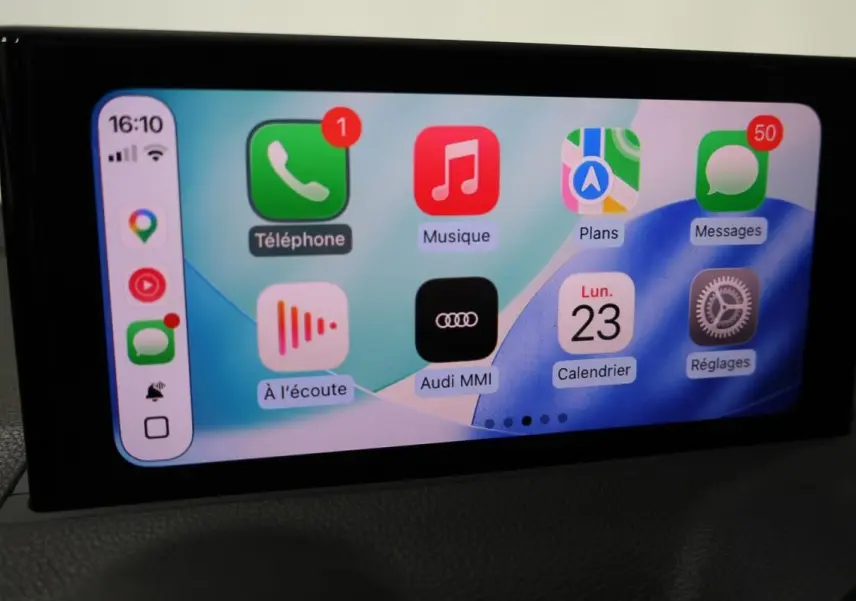 Écran tactile intérieur affichant l’interface Audi MMI avec applications GPS, téléphone et musique, vue de face.