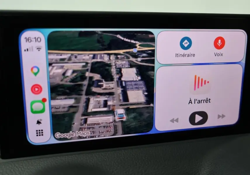 Écran central de l’Audi Q2 TFSI 110 gris 2023 affichant la navigation GPS en vue satellite et commandes vocales.