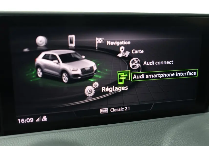 Écran central affichant l'interface multimédia avec une Audi Q2 grise en vue 3/4 avant stylisée.