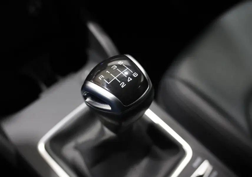 Le levier de vitesses manuel noir de l'Audi Q2 TFSI 110, vue rapprochée de l'intérieur côté conducteur.