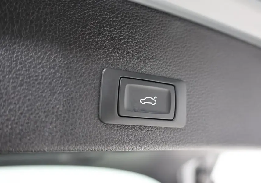 Bouton noir d'ouverture électrique du hayon sur garniture intérieure en cuir gris foncé de l'Audi Q2 2023.
