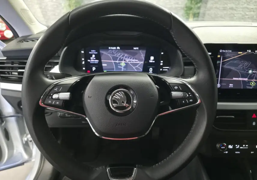 Vue rapprochée du volant cuir noir de la Skoda Kamiq 2023 avec tableau de bord digital et écran de navigation allumé.