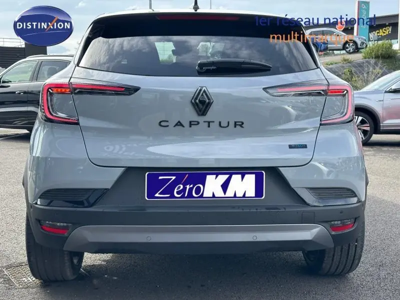 Vue arrière d'un Renault Captur 2026 gris Rafale avec toit noir étoilé, badge hybride et plaque Zéro KM visible.