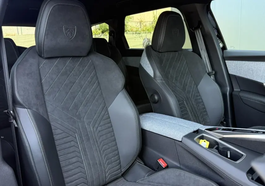 Vue rapprochée des sièges avant en Alcantara noir et tissu gris du Peugeot 5008 Hybrid GT, avec surpiqûres contrastées.