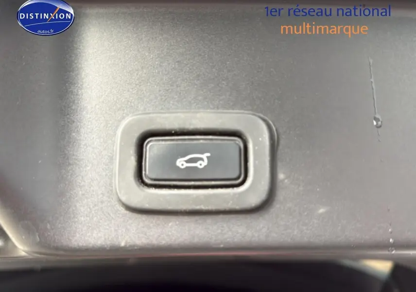 Bouton d'ouverture électrique du hayon sur le tableau de bord intérieur du Range Rover Evoque blanc et noir.