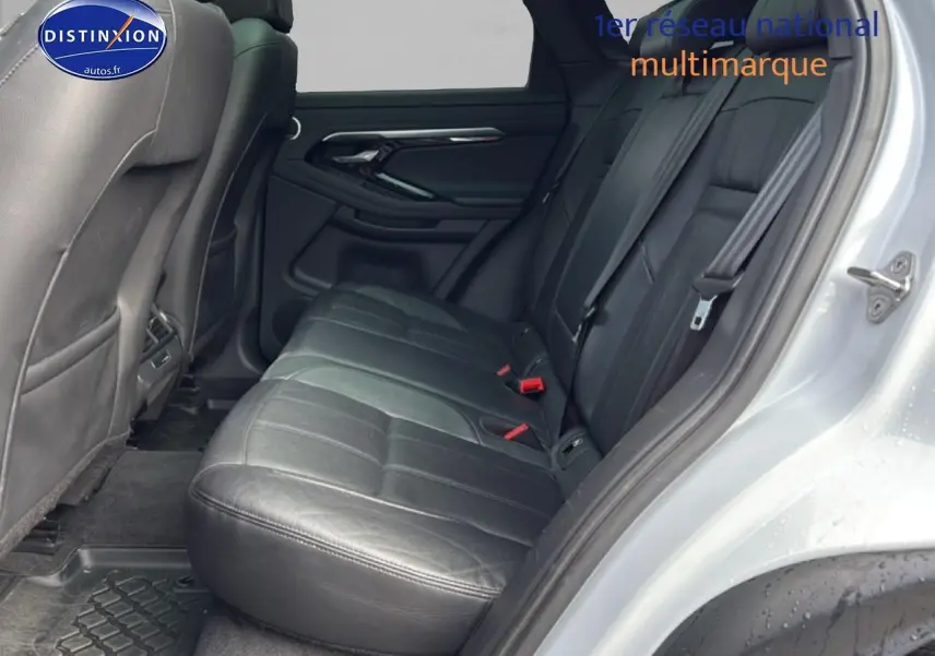 Vue intérieure côté droit sur la banquette arrière en cuir noir du Range Rover Evoque blanc, avec ceinture de sécurité visible.