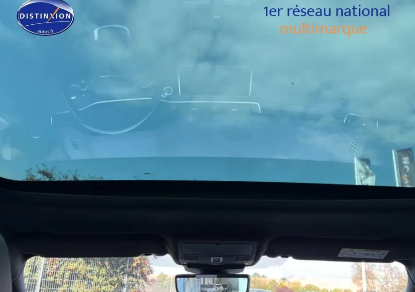 Vue intérieure du toit panoramique et du rétroviseur intérieur du Range Rover Evoque blanc, avec reflet extérieur visible.