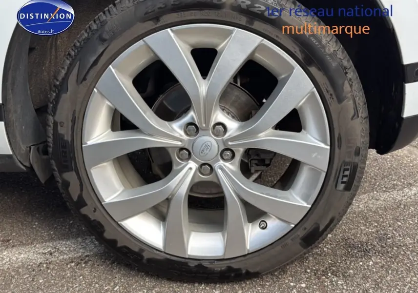 Gros plan sur la jante alu argentée et le pneu Pirelli du côté avant droit d’un Range Rover Evoque blanc.