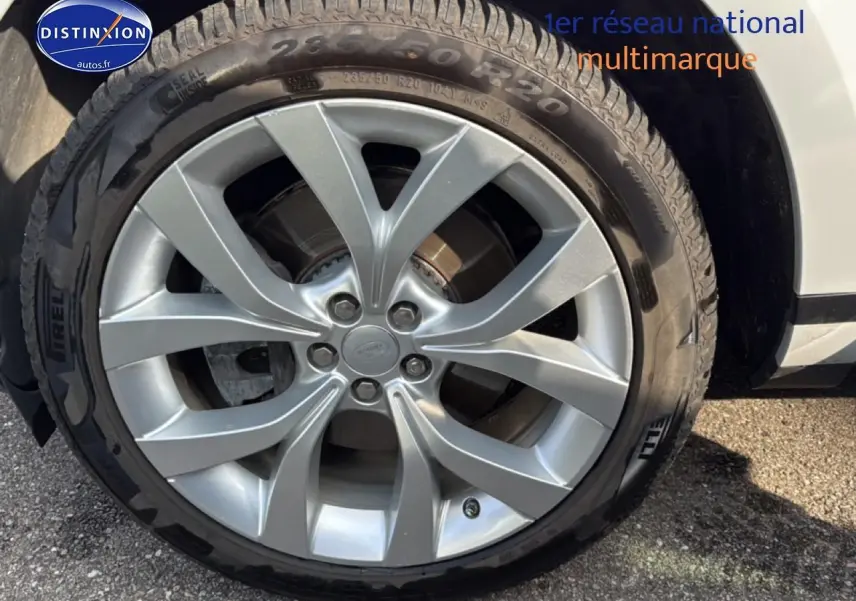 Gros plan sur la jante alu argentée et le pneu Pirelli du côté avant droit d’un Range Rover Evoque blanc.