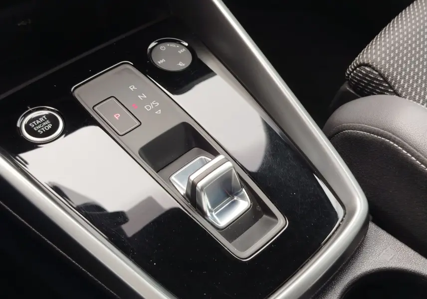 Gros plan sur la console centrale noire brillante de l’Audi A3 Sportback 30 TFSI avec sélecteur de boîte auto et bouton start/stop.