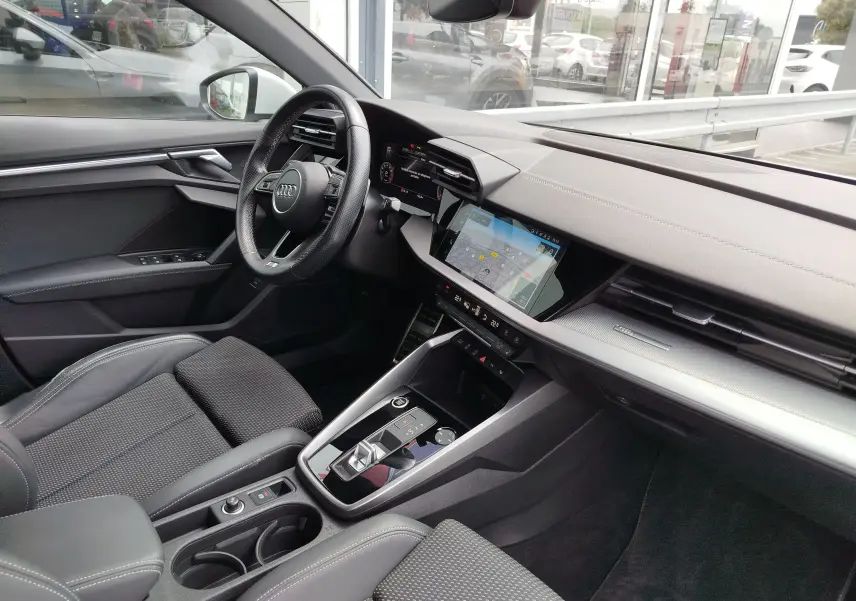 Vue intérieure côté conducteur de l'Audi A3 Sportback 2022 avec tableau de bord moderne et écran tactile central.