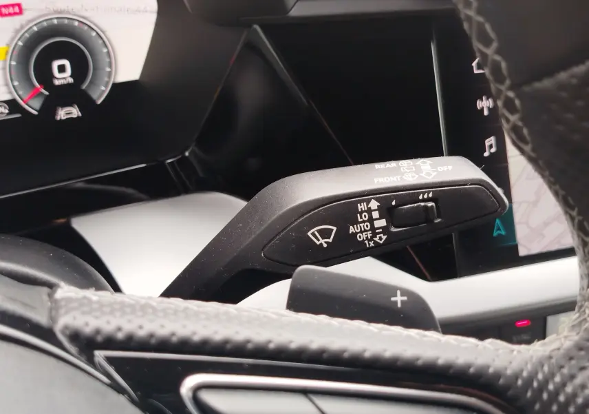 Gros plan sur la commande d’essuie-glace à gauche du volant dans l’habitacle d’une Audi A3 Sportback blanc Glacier 2022.