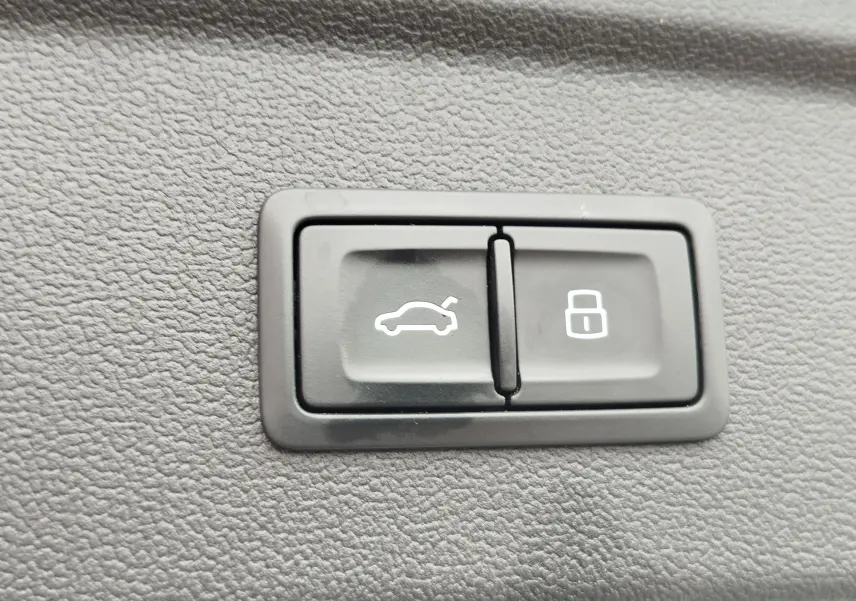 Gros plan sur les boutons d'ouverture du coffre et de verrouillage intérieur d'une Audi A3 Sportback blanc glacier.