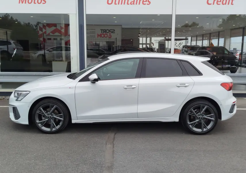 Audi A3 Sportback blanc Glacier métallisé vue de profil côté gauche, avec jantes alliage et vitres teintées.