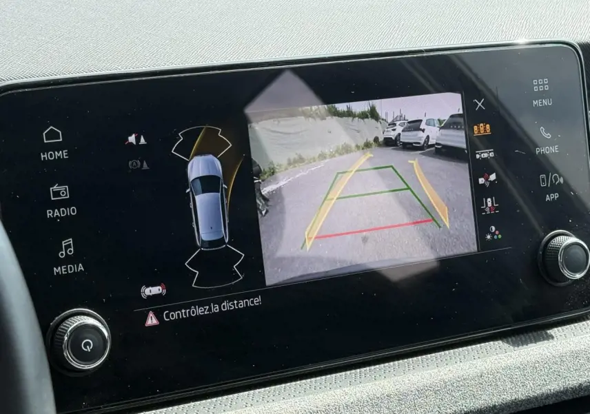 Écran central montrant la caméra de recul active avec vue arrière et alertes de distance du Skoda Scala gris graphite.