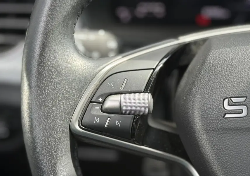 Gros plan sur le volant cuir gris avec commandes multifonctions et molette de réglage du volume du Skoda Scala TSI 116 Sélection.
