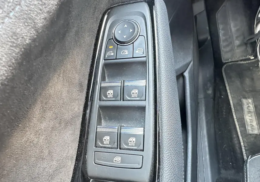 Gros plan sur les commandes de lève-vitres et rétroviseurs côté conducteur du Renault Austral 2024, intérieur noir.