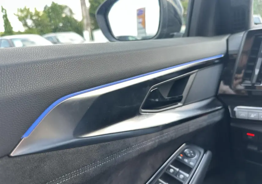 Détail de la porte côté conducteur du Renault Austral 2024 bleu toit noir, avec commandes de vitres et insert décoratif bleu.