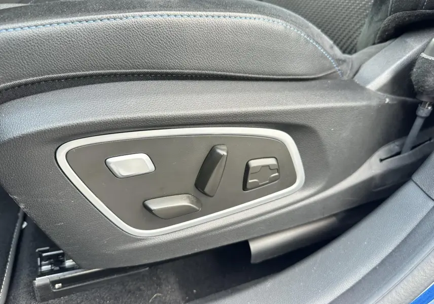 Gros plan sur les commandes électriques du siège conducteur du Renault Austral 2024 bleu toit noir.