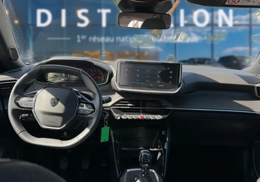 Vue intérieure avant du Peugeot 2008 gris 2025, volant multifonction, écran tactile et levier de boîte manuelle visibles.