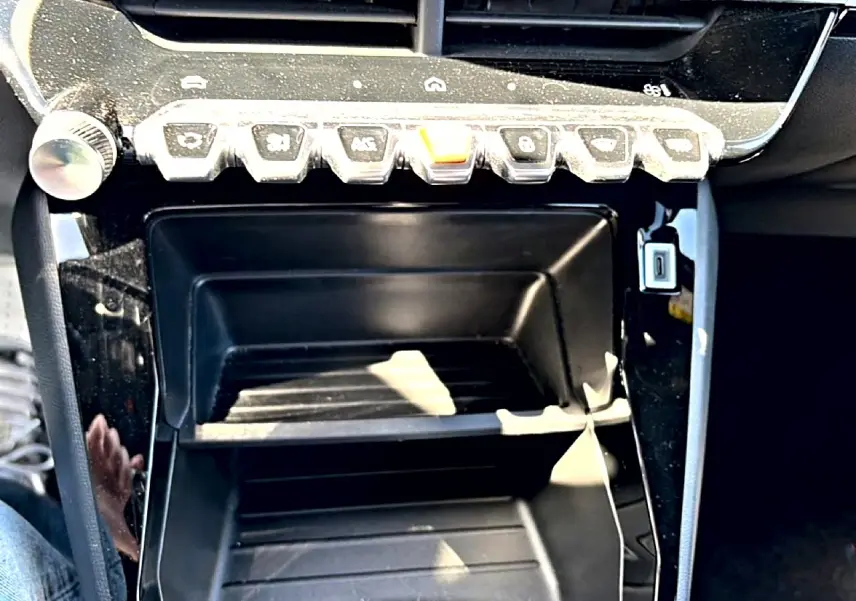 Gros plan sur la console centrale noire brillante du Peugeot 2008 1.2 100 style avec boutons de commande en rangée.