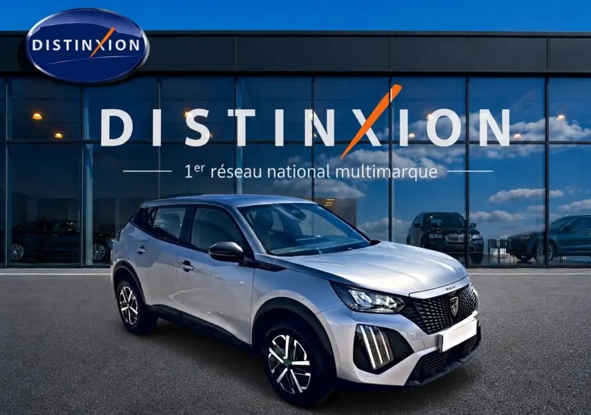 Peugeot 2008 gris 3/4 avant droit avec jantes distinctives et toit noir devant vitrine Distinxion.