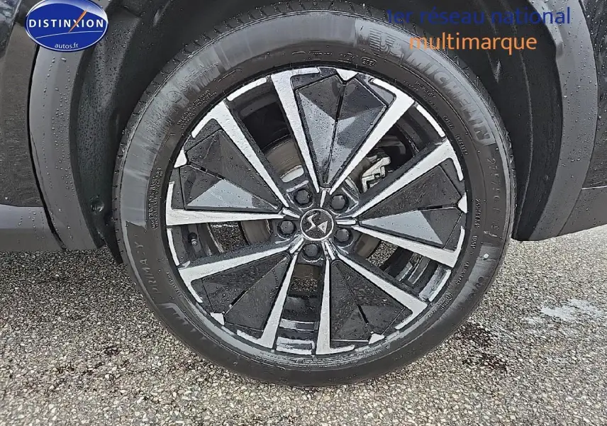 Gros plan sur la jante alu noire et argentée du côté gauche d'un DS7 noir 1.5 BlueHDi 130 Pallas 2025.