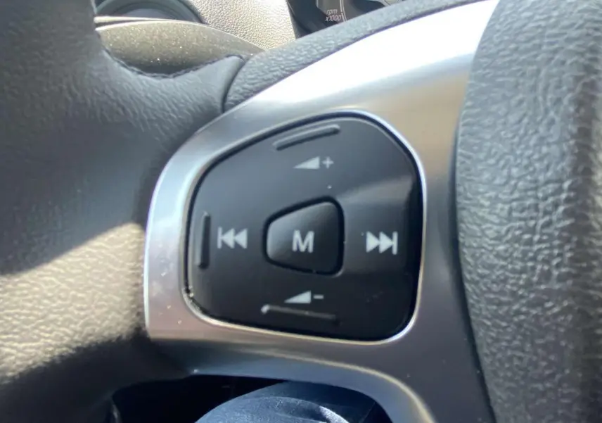 Gros plan sur les commandes audio au volant cuir noir du Ford Tourneo Courier blanc 2022, version Trend.