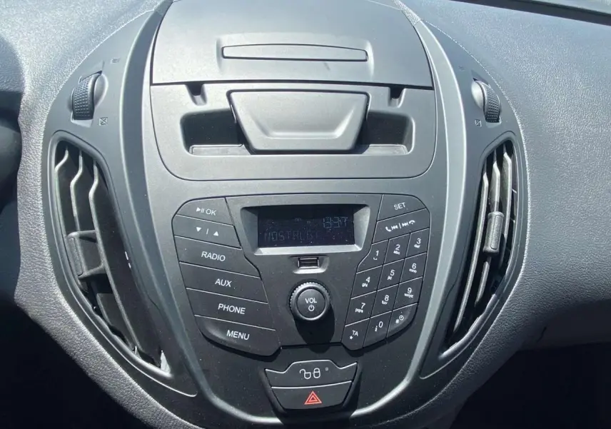 Vue rapprochée du tableau de bord noir du Ford Tourneo Courier 2022, mettant en valeur la console centrale avec radio et commandes.