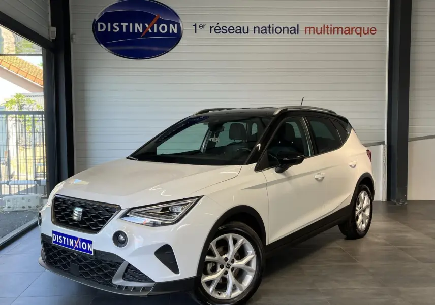 SEAT Arona blanc Nevada 2024 en 3/4 avant droit avec toit noir et jantes alliage 16 pouces en showroom