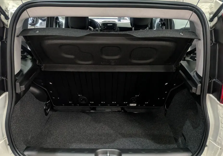 Coffre ouvert vu de l'arrière d'une Fiat Panda 1.0 70 CH Hybrid City blanc Gelato, intérieur noir et gris.