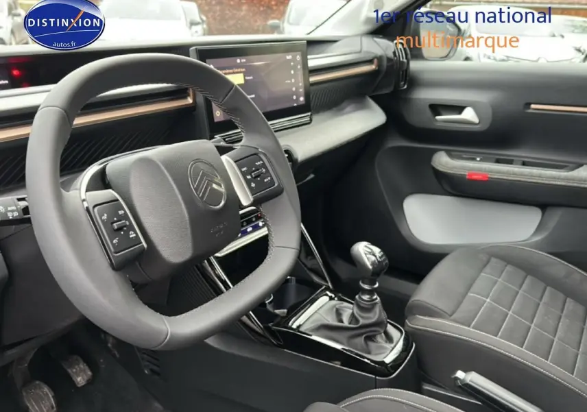 Intérieur gris du Citroën C3 Aircross 2025, vue côté conducteur sur volant multifonction et levier de vitesse manuel.