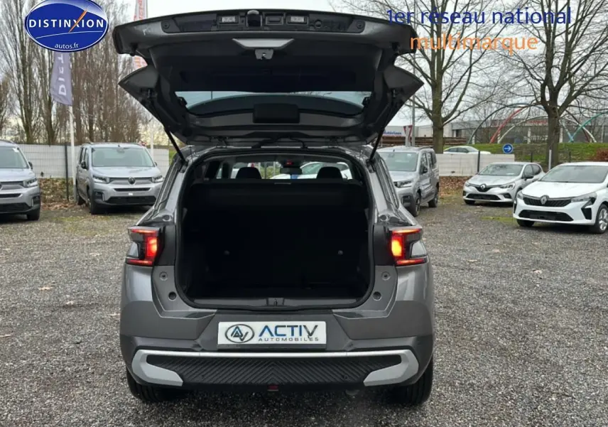 Vue arrière d'une Citroën C3 Aircross gris 2025 avec coffre ouvert et feux arrière allumés sur parking extérieur.