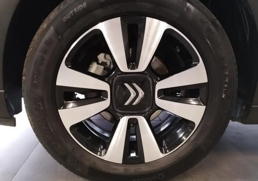 Gros plan sur la jante alliage 16 pouces diamantée noir et argent d'une Citroën C3 gris foncé, avec logo central double chevron.