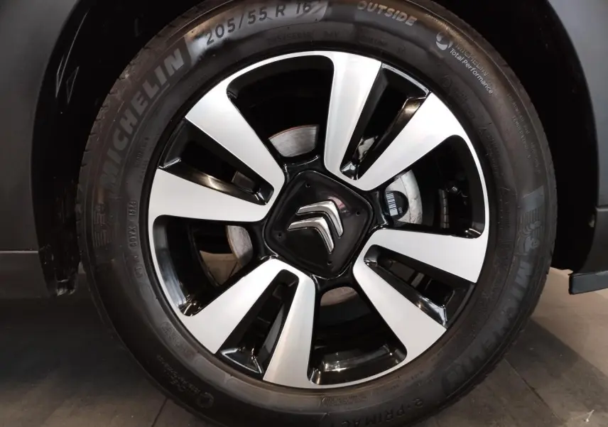 Gros plan sur la jante alliage diamantée 16 pouces noire et argentée de la Citroën C3 gris foncé.