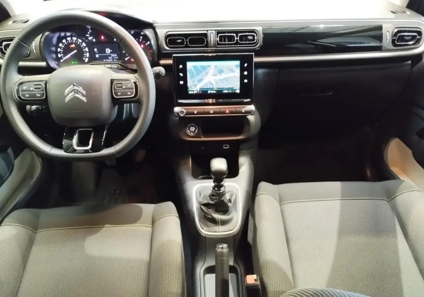 Vue intérieure avant de la Citroën C3 2024 avec tableau de bord noir brillant, volant multifonction et écran tactile central.