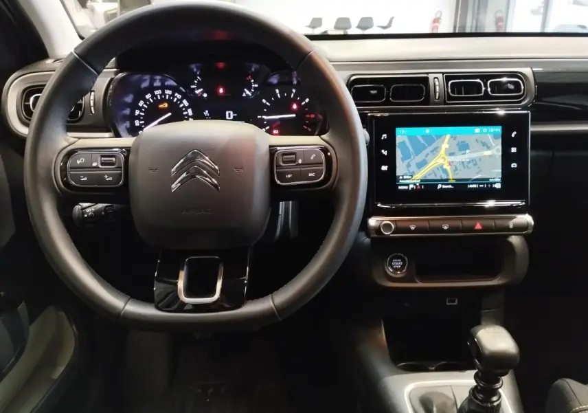 Vue intérieure frontale du poste de conduite de la Citroën C3 2024 avec volant multifonction et écran tactile de navigation.