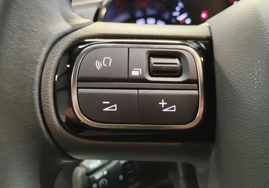 Gros plan sur les commandes au volant noir brillant de la Citroën C3 2024, boutons de réglage du volume et appels.