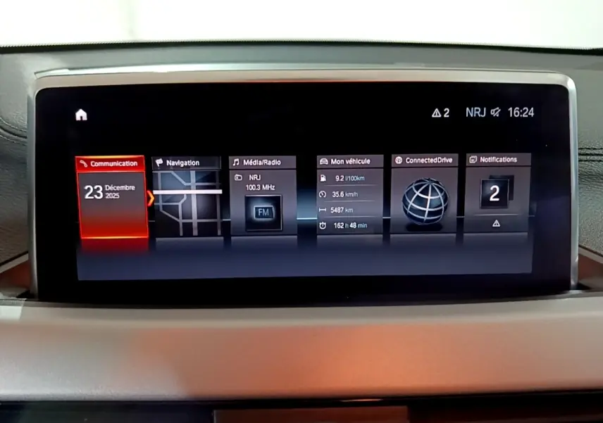 Écran central tactile du tableau de bord du BMW X2 noir, affichant navigation, radio et infos véhicule.