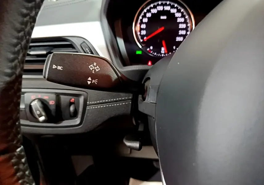 Gros plan intérieur sur le volant noir en cuir et la commande de clignotants du BMW X2 sDrive18i Lounge 2023.