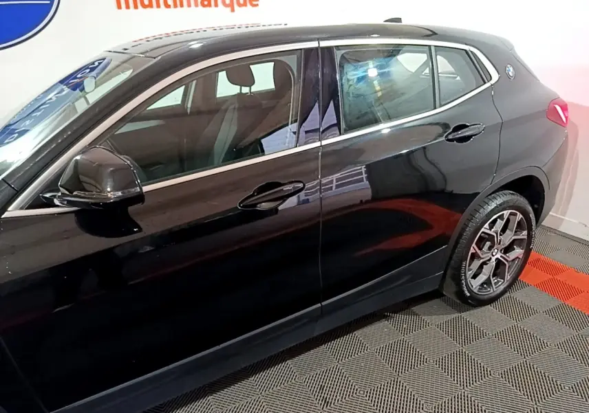 BMW X2 sDrive18i Lounge noir vue de profil côté gauche, avec jantes alliage et rétroviseur électrique.