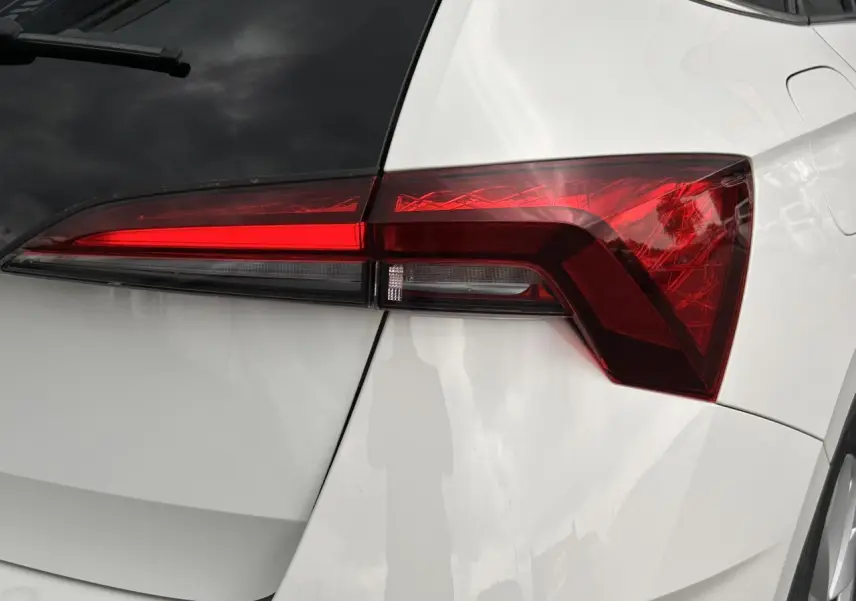 Gros plan sur le feu arrière droit rouge vif d'une SKODA SCALA 2025 blanc Candy avec lunette arrière surteintée.