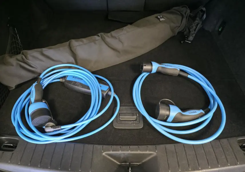 Vue du coffre noir du Mazda CX-60 gris avec deux câbles de recharge bleu clair enroulés.